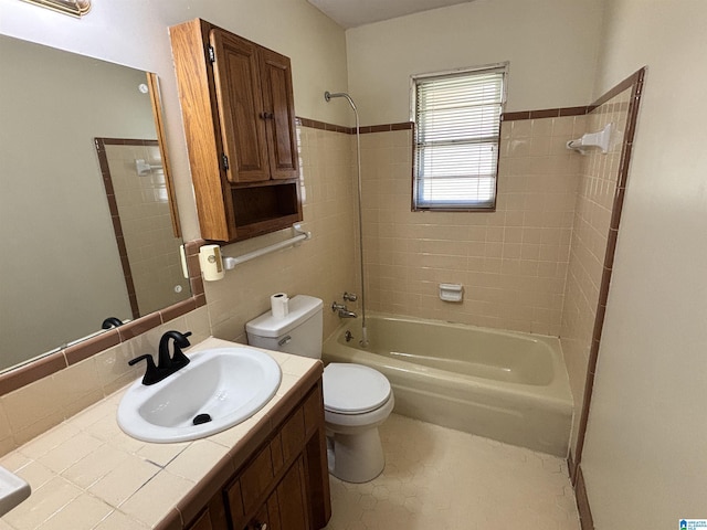 full bathroom featuring tiled shower / bath combo, tile patterned floors, toilet, vanity, and tile walls