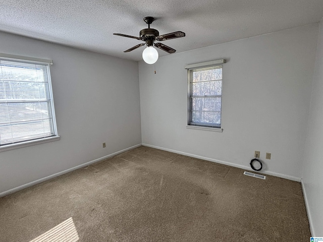 carpeted spare room featuring plenty of natural light, ceiling fan, and a textured ceiling