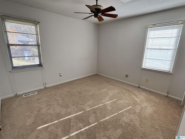 carpeted spare room featuring ceiling fan and a textured ceiling