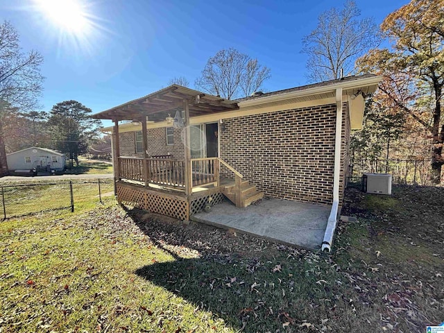 rear view of property featuring a lawn, a patio, and a deck