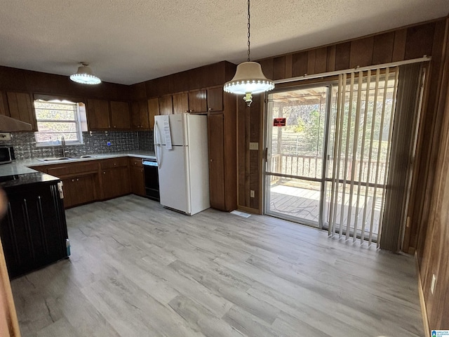 kitchen featuring pendant lighting, light wood-type flooring, white fridge, and sink