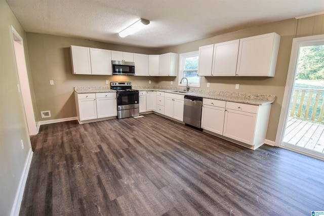 kitchen with appliances with stainless steel finishes, white cabinetry, sink, and dark hardwood / wood-style flooring