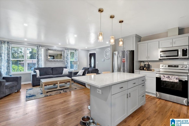 kitchen featuring light stone counters, stainless steel appliances, light hardwood / wood-style floors, decorative light fixtures, and a center island