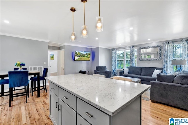 kitchen featuring light hardwood / wood-style floors, a healthy amount of sunlight, decorative light fixtures, and a kitchen island