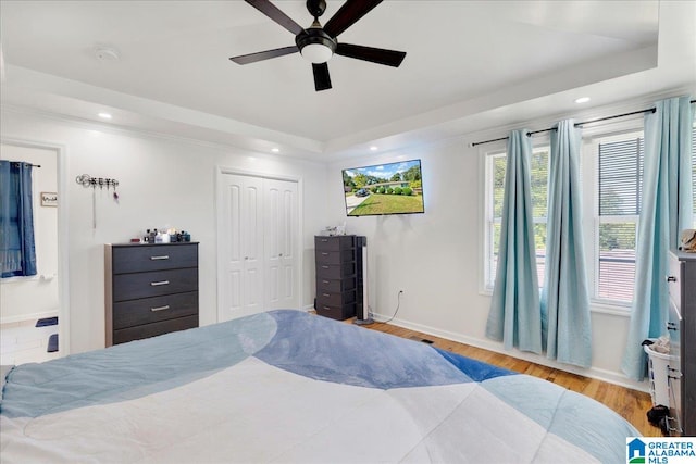 bedroom with light wood-type flooring, ensuite bath, a closet, ceiling fan, and ornamental molding