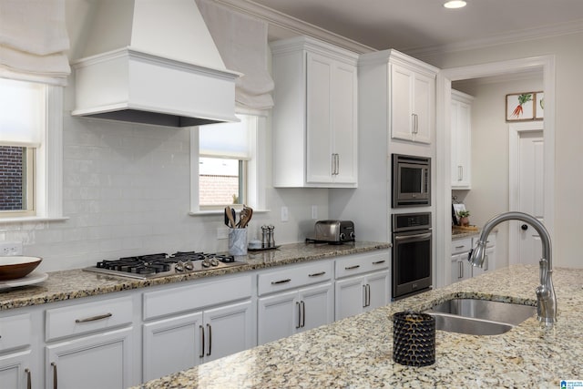 kitchen with decorative backsplash, white cabinetry, custom range hood, sink, and stainless steel appliances