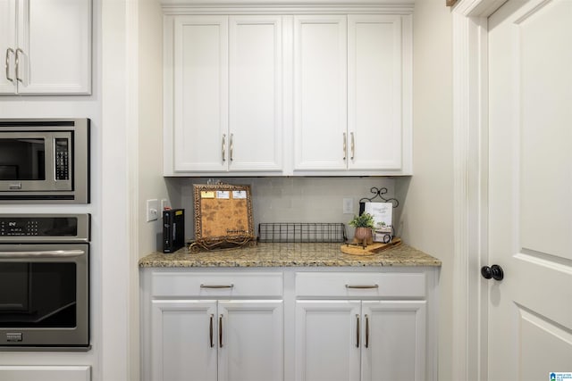 bar with backsplash, appliances with stainless steel finishes, and white cabinets