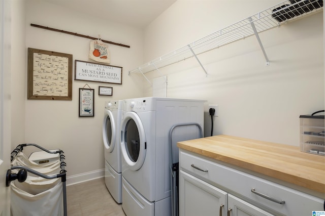 laundry room featuring washing machine and clothes dryer and cabinets