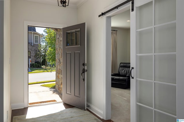 foyer entrance featuring ornamental molding, a barn door, and carpet floors