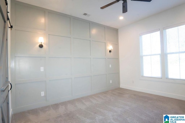 interior space with light colored carpet, ceiling fan, and a barn door