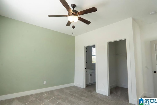 unfurnished bedroom with a spacious closet, a closet, ceiling fan, connected bathroom, and light colored carpet