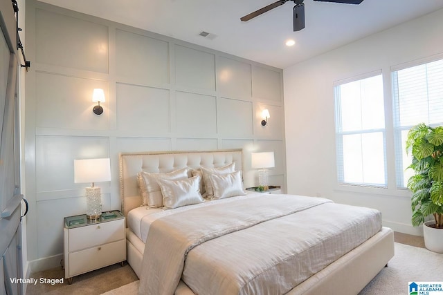 bedroom featuring a barn door, light colored carpet, and ceiling fan