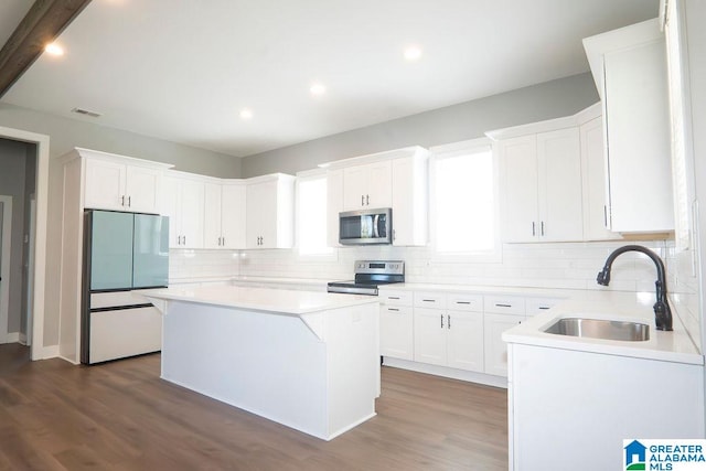 kitchen with appliances with stainless steel finishes, a kitchen island, and white cabinets