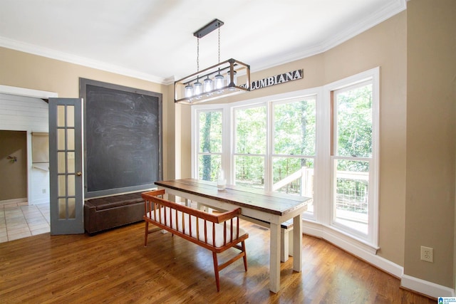 dining space featuring a healthy amount of sunlight, crown molding, hardwood / wood-style flooring, and a chandelier