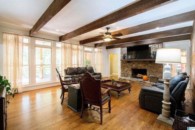 living room featuring beam ceiling, a stone fireplace, light hardwood / wood-style flooring, and ceiling fan