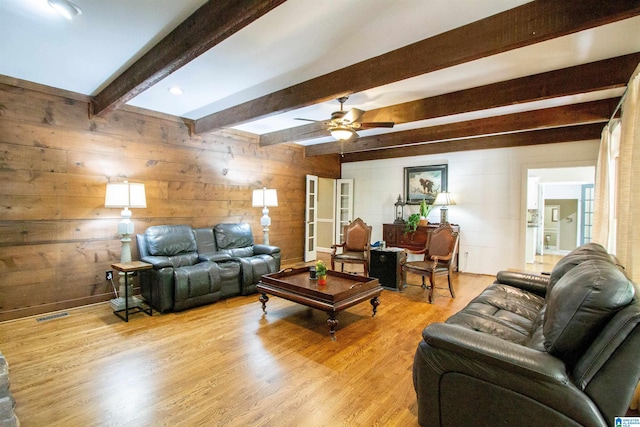 living room featuring light hardwood / wood-style floors, wood walls, beamed ceiling, and ceiling fan