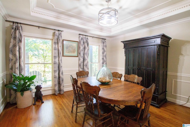 dining space with light hardwood / wood-style flooring, a raised ceiling, ornamental molding, and a wealth of natural light