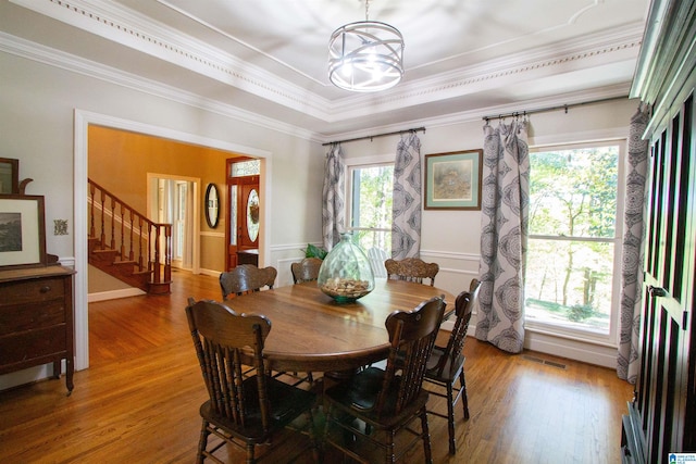 dining area featuring crown molding, a tray ceiling, a chandelier, and wood-type flooring