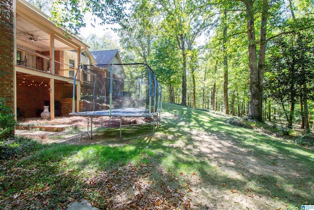 view of yard with a trampoline and ceiling fan