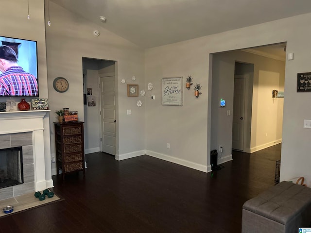 living room featuring crown molding, a tiled fireplace, and dark wood-type flooring