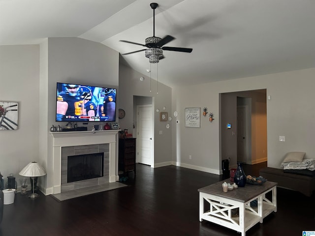 living room featuring lofted ceiling, dark wood-type flooring, a tiled fireplace, and ceiling fan