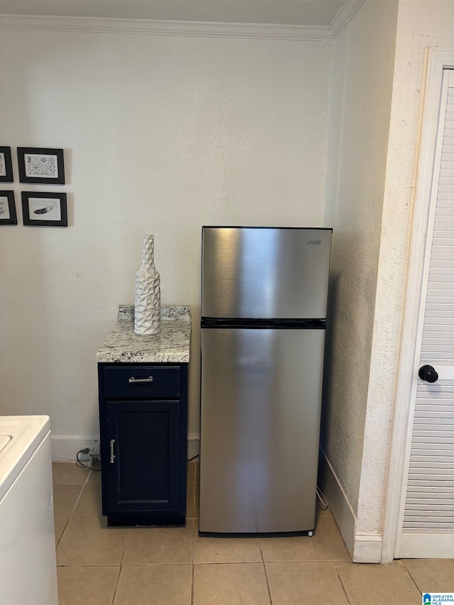 kitchen with crown molding, washer / clothes dryer, light tile patterned floors, and stainless steel fridge