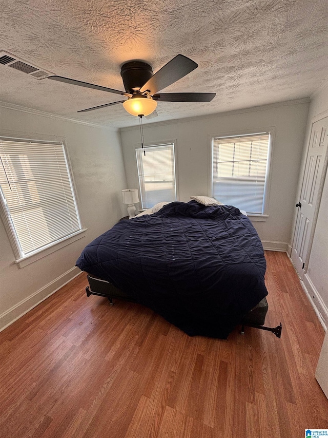 bedroom featuring ceiling fan, a textured ceiling, and light wood-type flooring