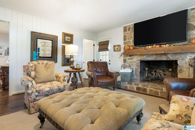 living room featuring a stone fireplace and wood-type flooring