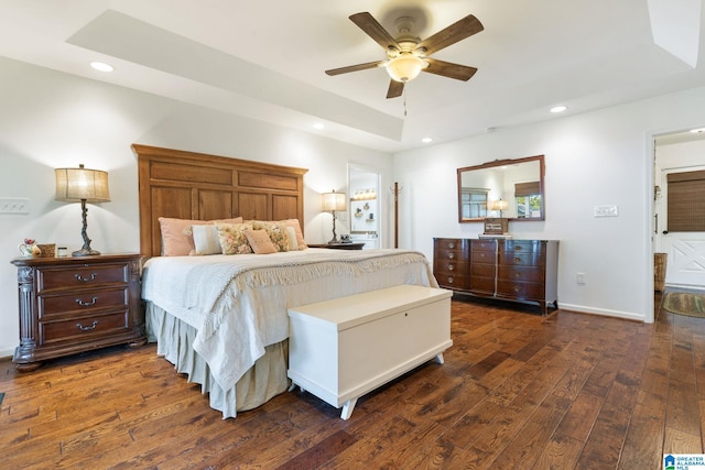 bedroom featuring ceiling fan, dark hardwood / wood-style flooring, and a tray ceiling