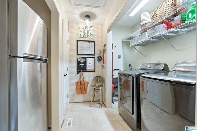 laundry area featuring light tile patterned flooring, a textured ceiling, and independent washer and dryer