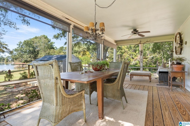 sunroom with a wealth of natural light, a water view, and ceiling fan with notable chandelier