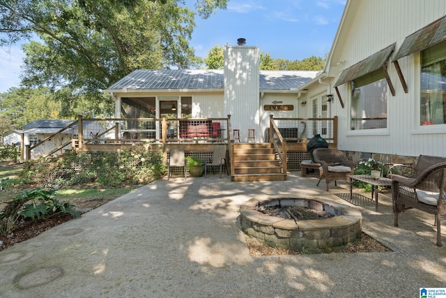 back of property with a fire pit, a patio area, and a deck