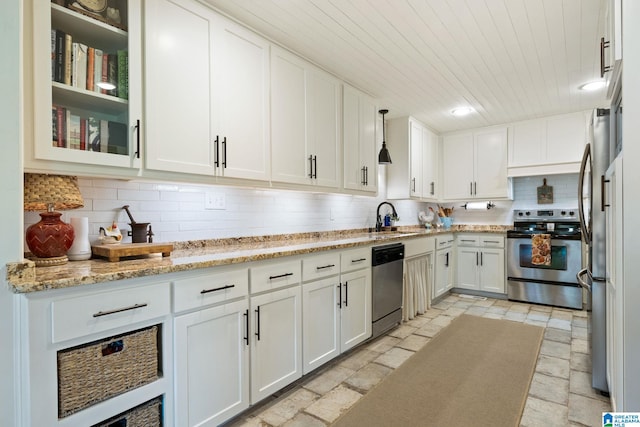 kitchen with white cabinetry, appliances with stainless steel finishes, light stone countertops, hanging light fixtures, and sink