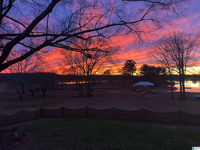 yard at dusk featuring a water view and a gazebo