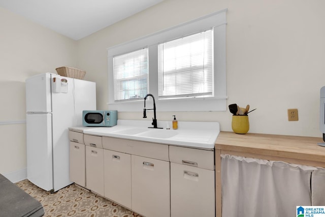 kitchen with white appliances, white cabinetry, and sink