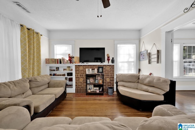 living room with ceiling fan, hardwood / wood-style flooring, and a textured ceiling