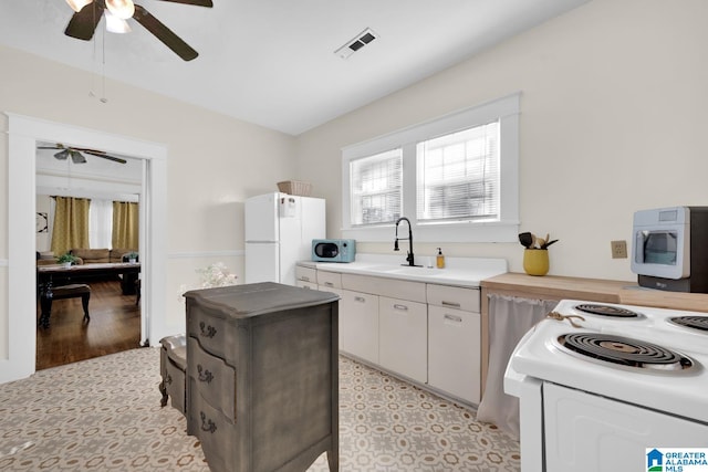 kitchen with sink, light wood-type flooring, white cabinets, white fridge, and ceiling fan