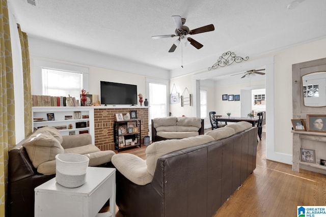 living room featuring light hardwood / wood-style flooring, a textured ceiling, and ceiling fan