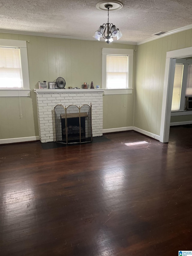 1244 15th St, Birmingham, AL 35211 - unfurnished living room featuring a textured ceiling, ornamental molding, a brick fireplace, wood finished floors, and a chandelier