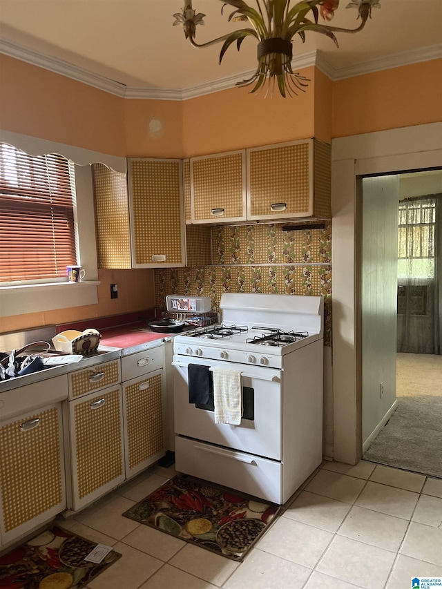 1244 15th St, Birmingham, AL 35211 - kitchen featuring white gas range oven, crown molding, light tile patterned floors, and dark countertops