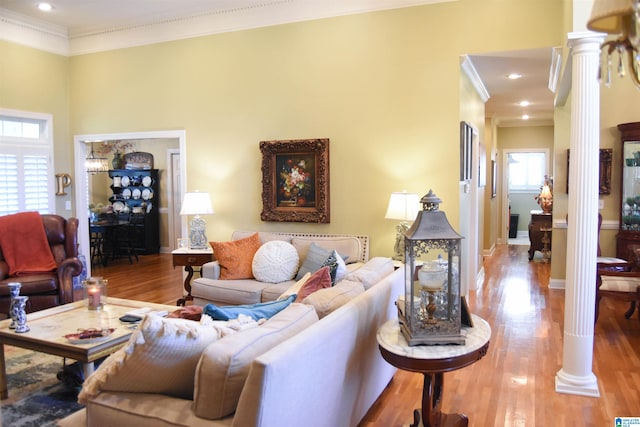 living room with a towering ceiling, ornate columns, crown molding, and wood-type flooring