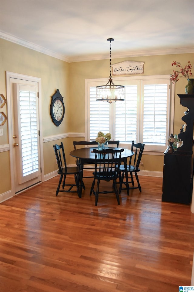 dining room with dark wood-type flooring, crown molding, and an inviting chandelier