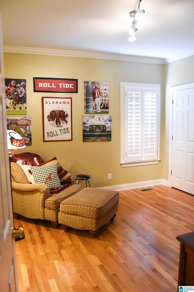 living area featuring rail lighting, crown molding, and hardwood / wood-style floors