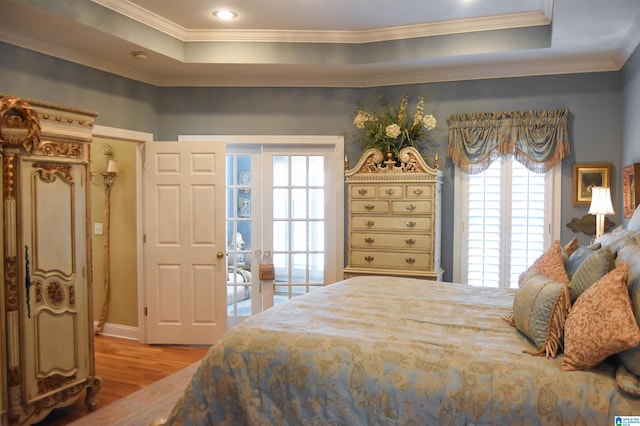 bedroom featuring crown molding, light hardwood / wood-style floors, and a raised ceiling