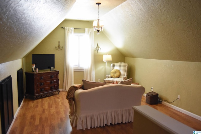 sitting room featuring a textured ceiling, vaulted ceiling, wood-type flooring, and an inviting chandelier