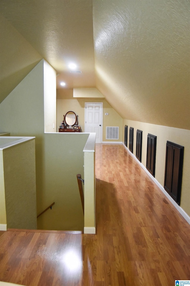 bonus room featuring a textured ceiling, vaulted ceiling, and hardwood / wood-style flooring