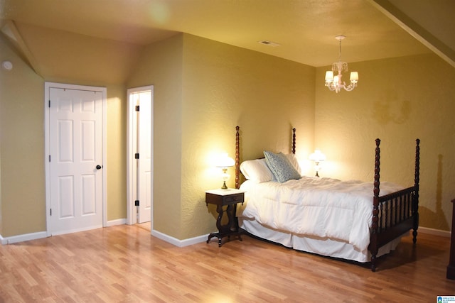 bedroom featuring lofted ceiling, a chandelier, and hardwood / wood-style flooring