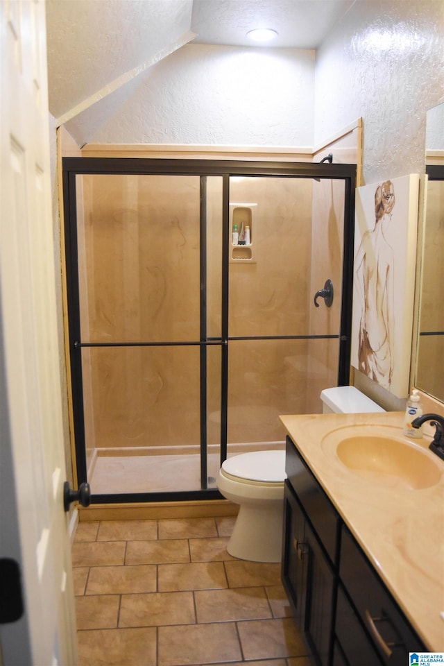 bathroom featuring lofted ceiling, tile patterned floors, toilet, vanity, and walk in shower