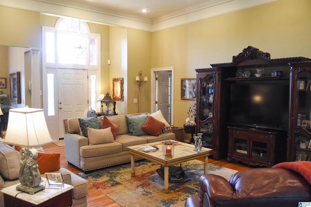 living room with a towering ceiling, light hardwood / wood-style flooring, and ornamental molding