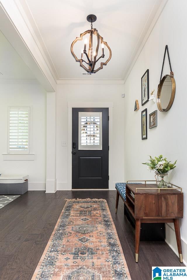 foyer featuring an inviting chandelier, dark hardwood / wood-style flooring, and ornamental molding